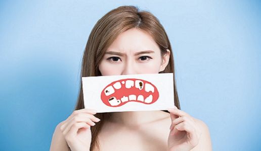 Woman holding up a graphic of a mouth with cavities on teeth.